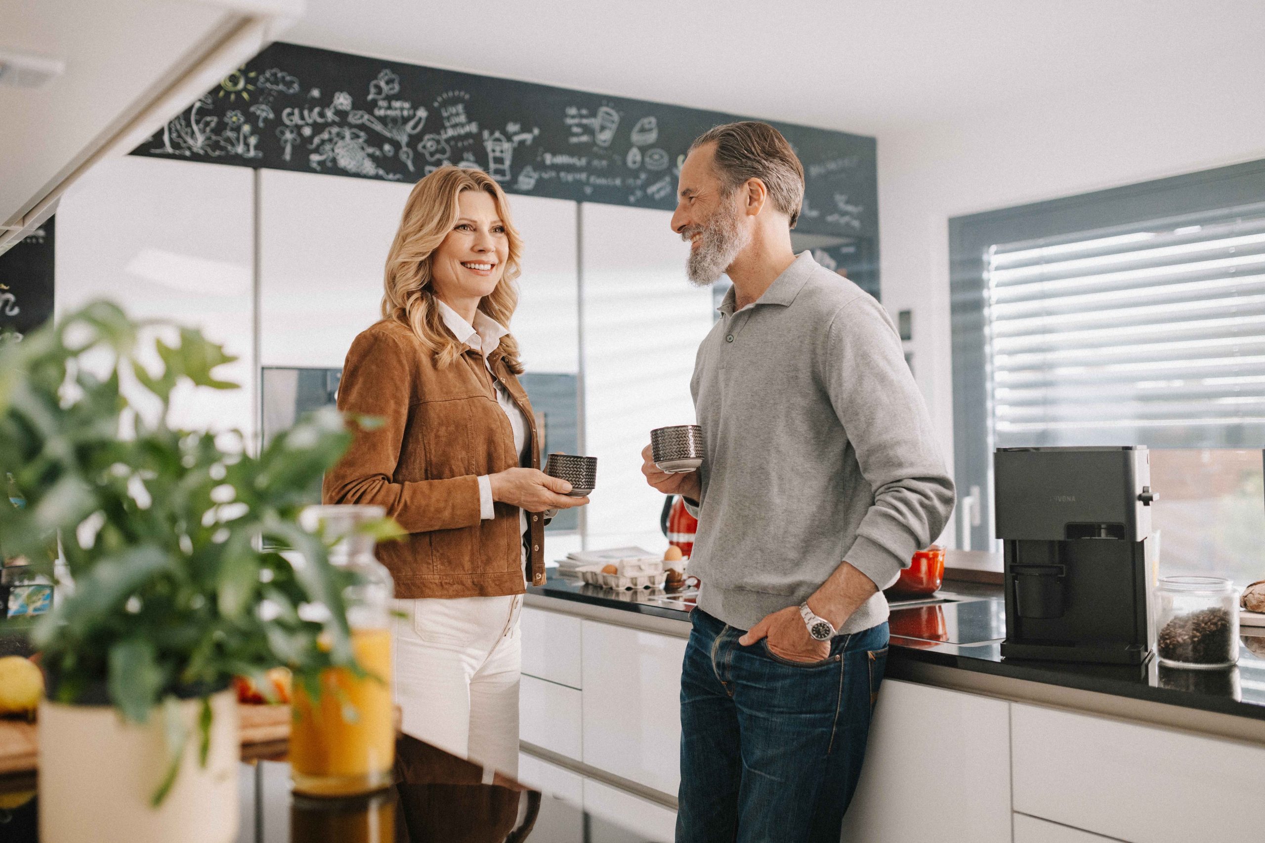 This picture was taken for a client called Nivona, who's a manufacturer for coffee machines. Two adults are standing in a modern kitchen holding coffee mugs. The coffee machine is standing next to them.